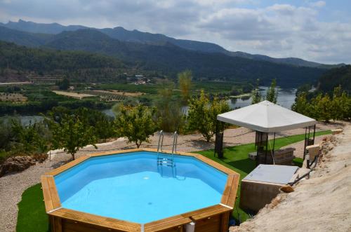 a swimming pool with a view of a river and mountains at Mas del Fangaro in Benifallet