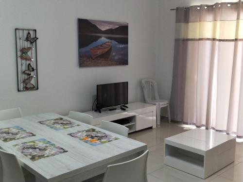 a white dining room with a table and a tv at SunStone Court in St. Paul's Bay
