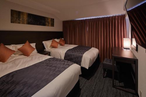 a hotel room with two beds and a desk at Centurion Hotel & Spa Kurashiki Station in Kurashiki