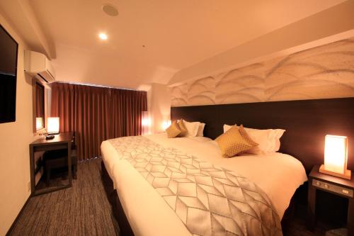a hotel room with a large bed and two lamps at Centurion Hotel & Spa Kurashiki Station in Kurashiki