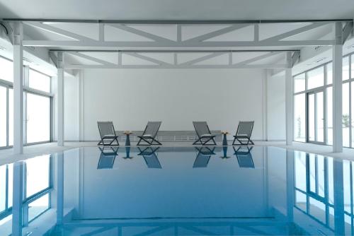 a pool with chairs and tables in a room with windows at INNSiDE by Meliá Palma Bosque in Palma de Mallorca