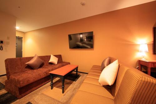a living room with a couch and a table at Centurion Hotel & Spa Kurashiki Station in Kurashiki