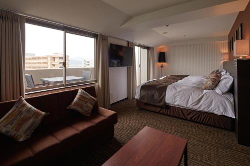 a hotel room with a bed and a couch at Centurion Hotel & Spa Kurashiki Station in Kurashiki