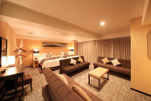 a hotel room with a bed and a couch at Centurion Hotel & Spa Kurashiki Station in Kurashiki