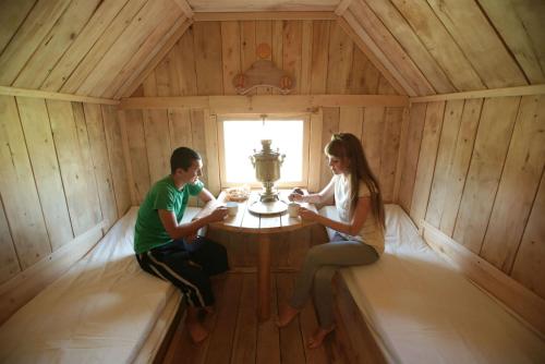 un hombre y una mujer sentados en una mesa en una habitación de madera en Gluhoman, en Poltava