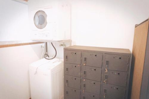a laundry room with a refrigerator and a microwave at Book & Guesthouse Hitotomaru in Toyooka