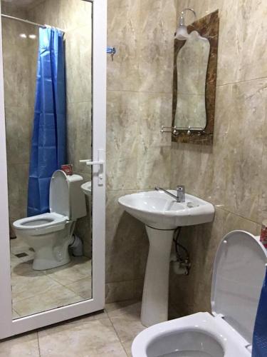 a bathroom with a sink and a toilet and a mirror at Wooden Cottage in Makhinjauri