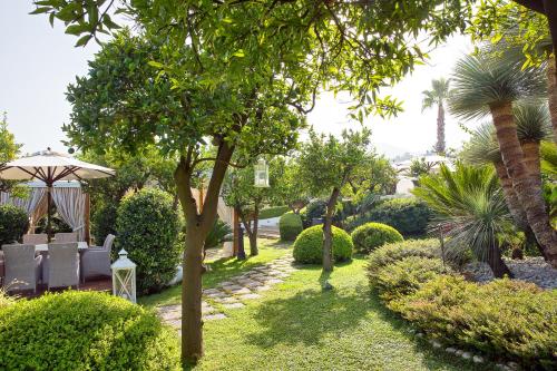 a garden with chairs and an umbrella and trees at La Medusa Hotel - Dimora di Charme in Castellammare di Stabia