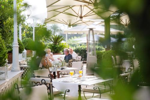 a group of people sitting at a restaurant with tables and umbrellas at La Medusa Hotel - Dimora di Charme in Castellammare di Stabia