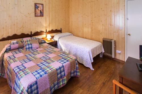 1 dormitorio con 2 camas y mesa con lámpara en Pension Restaurante Cantábrico en Cariño