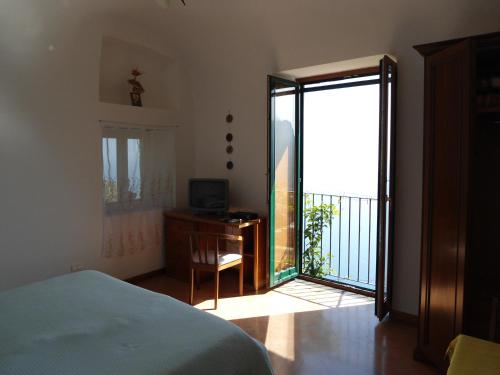 Schlafzimmer mit einem Bett und einer Tür zu einem Balkon in der Unterkunft Le Ghiande in Positano
