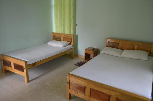 two twin beds in a room withthritisthritislictslictslicts at Gnanam Holiday Inn in Pasikuda