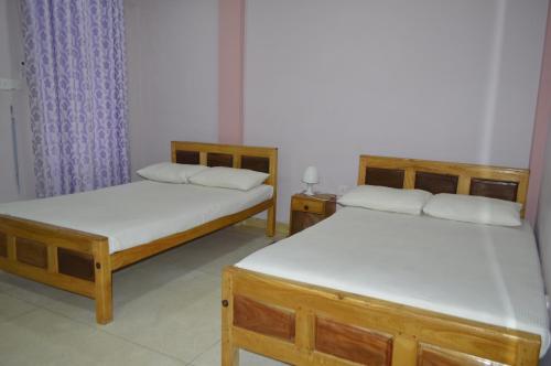 two twin beds in a room withthritisthritis at Gnanam Holiday Inn in Pasikuda
