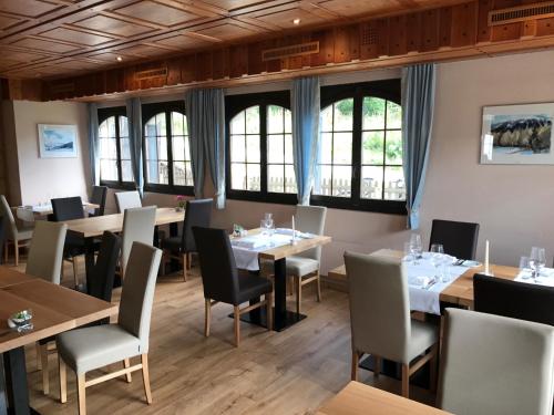 a dining room with tables and chairs and windows at Hotel Restaurant Zur alten Gasse in Bellwald