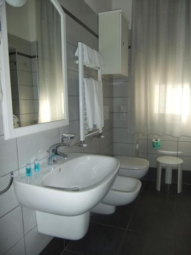 - une salle de bains blanche avec 2 toilettes et un lavabo dans l'établissement Hotel Giulio Cesare, à Cinquale