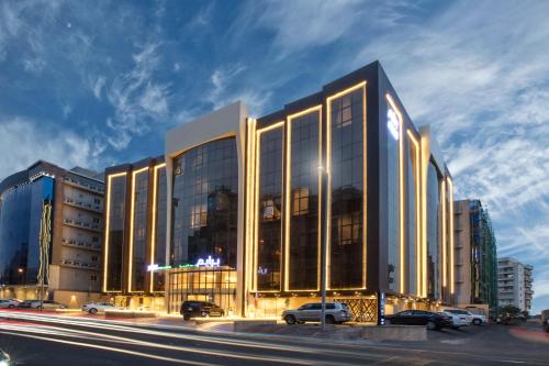 a large glass building with cars parked in a parking lot at Prime Al Hamra Hotel in Jeddah