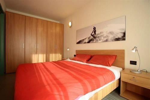 una camera da letto con un letto con lenzuola rosse e un dipinto di Attico Villaggio Olimpico Sestriere a Sestriere