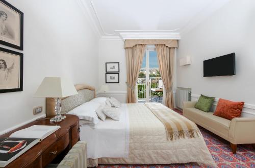 a bedroom with a bed and a couch and a television at La Medusa Hotel - Dimora di Charme in Castellammare di Stabia