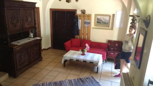 ein Kind steht in einem Wohnzimmer mit einem roten Sofa in der Unterkunft Gospoda w Starym Młynie in Jugowice