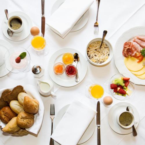 a table with plates of breakfast food on it at Hotel Hirsch in Kehl am Rhein
