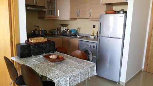 a kitchen with a table and a white refrigerator at Asilah marina golf in Asilah
