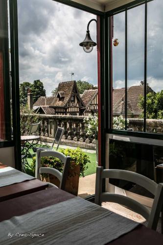a room with a view of a house through a window at Logis Hotel La Tourelle du Beffroi in Bourbon-Lancy