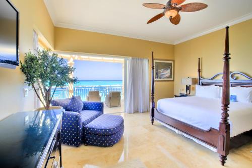 a bedroom with a bed and a chair and a television at Windsong on the Reef in Grace Bay