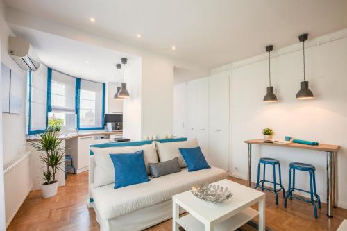 Terrace Apartments at City Park في بودابست: غرفة معيشة مع أريكة بيضاء ووسائد زرقاء
