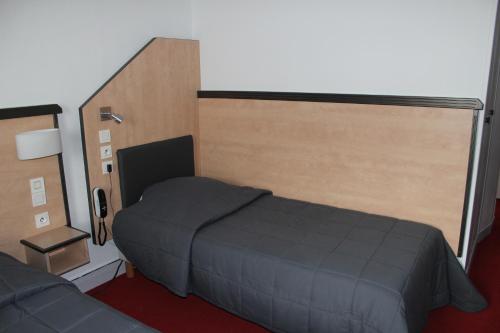 a small bedroom with a bed and a couch at Hôtel de la Meuse in Charleville-Mézières