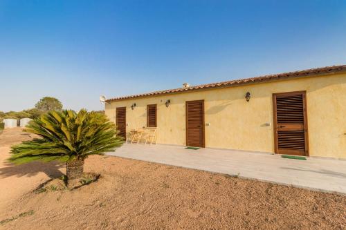 a house in the desert with a palm tree in front at Molti Mari B&B Resort in Olbia