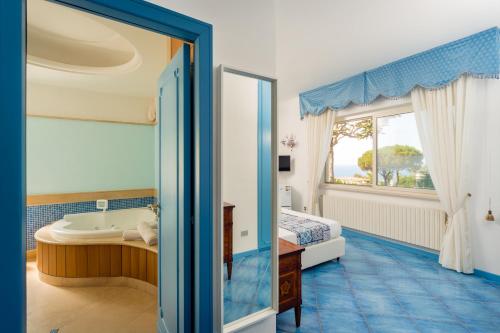 a bedroom with a tub and a bed and a window at Villa Araucaria in Ischia
