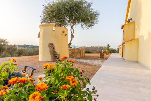 a cat sitting next to a building with flowers at Molti Mari B&B Resort in Olbia