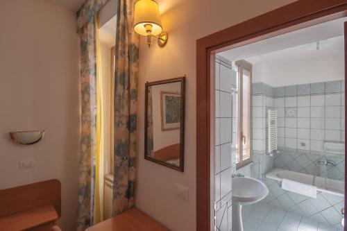 ein Badezimmer mit einer Badewanne, einem Waschbecken und einem Spiegel in der Unterkunft Hotel Tirreno in Rom