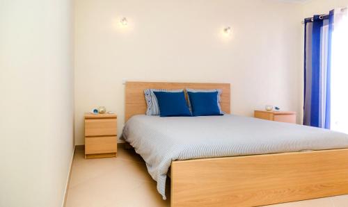 a bedroom with a large bed with blue pillows at For Sea Apartment in Cabanas de Tavira