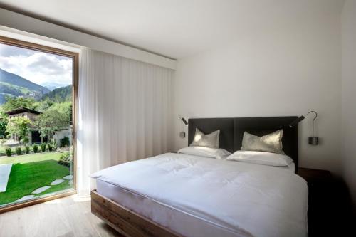 a bedroom with a bed and a large window at Residence Villa Calluna in Campo Tures