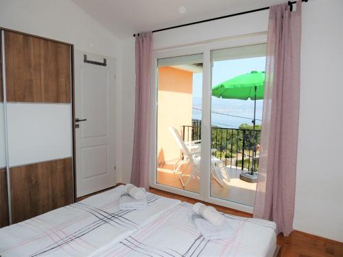 a bedroom with a bed and a balcony with an umbrella at Apartment Cindy in Lovran