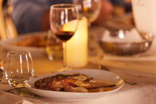 Alba D'Amore Hotel & Spa في لامبيدوسا: طبق من الطعام على طاولة مع كوب من النبيذ