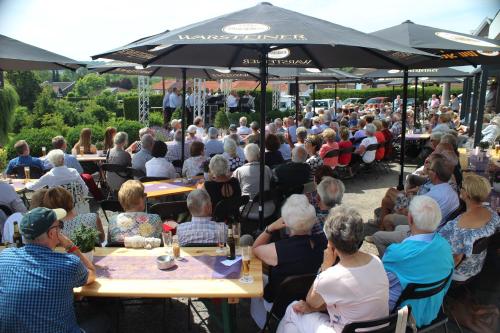 een grote menigte mensen zitten aan tafels onder parasols bij Hotel Salden in Schin op Geul