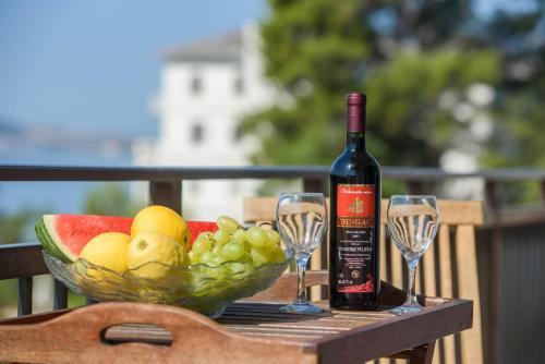 Luxury Rooms Ivana في قشتيلا: زجاجة من النبيذ ووعاء من الفواكه وكؤوس النبيذ