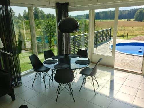 a dining room with a table and chairs and a pool at Villa Vihti in Ojakkala