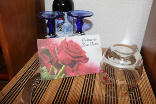 a table with two vases and a sign and a glass at Casa Teresinha in Sesimbra