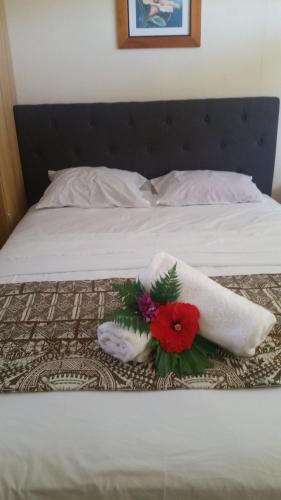 a bed with two towels and a bouquet of flowers at Samoa Home in Vaitele