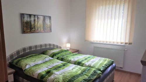 Un dormitorio con una cama con almohadas verdes y una ventana en Pinewood Valley Oasis en Vyšné Ružbachy