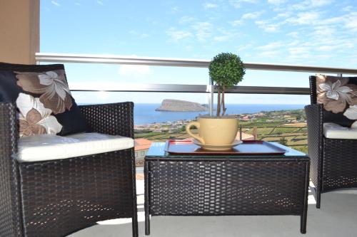 a patio with chairs and a table with a plant on it at Cantinho da Bela Vista in Porto Judeu