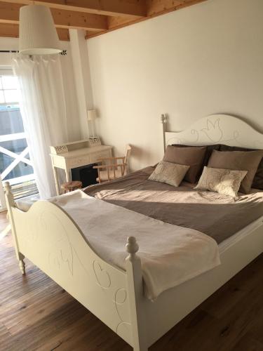 a white bed in a bedroom with a desk at Zimmer mit Bad und Balkon in Widen