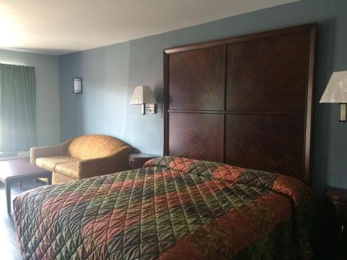 a hotel room with a bed and a chair at Gulf American Inns in Decatur