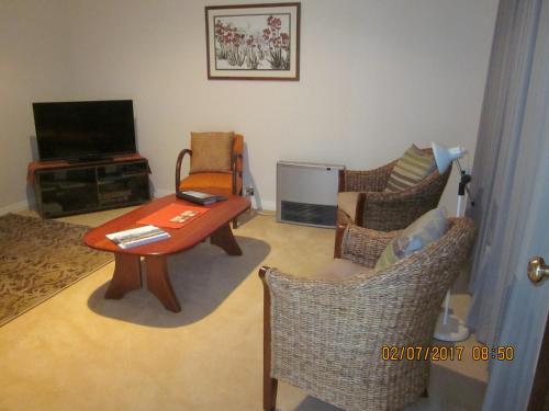 ein Wohnzimmer mit einem Tisch, Stühlen und einem TV in der Unterkunft Cusack's of Albany in Albany