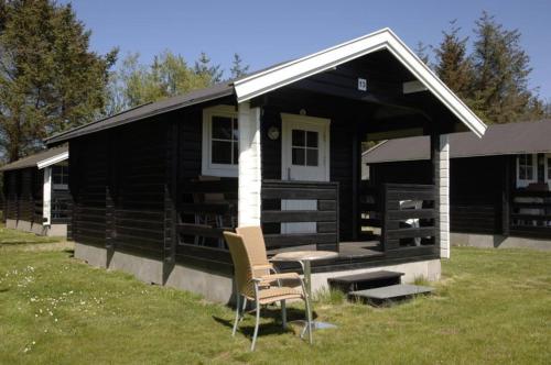 a black cabin with a table and chairs in front of it at Løkken Klit Camping & Cottage Village in Løkken