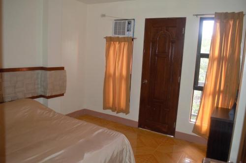 a bedroom with a bed and a window and a door at Manora Apartment in Talisay