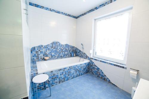 ein blau gefliestes Bad mit einer Badewanne und einem Fenster in der Unterkunft Bett & Bike Eden in Senftenberg